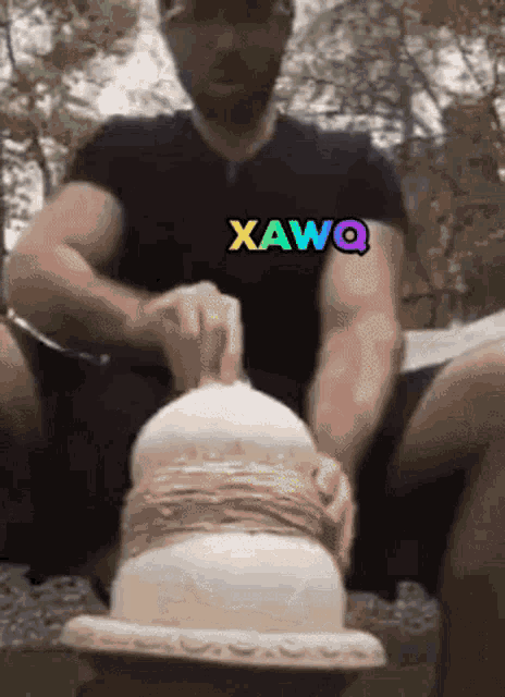 a man wearing a black shirt with xwq written on it is making a sculpture