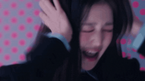a woman is covering her ears with her hand and crying .
