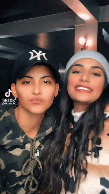 two women are posing for a picture and one has a hat that says ny