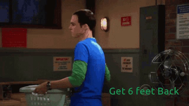 a man in a blue shirt is holding a laundry basket with the words get 6 feet back on the bottom