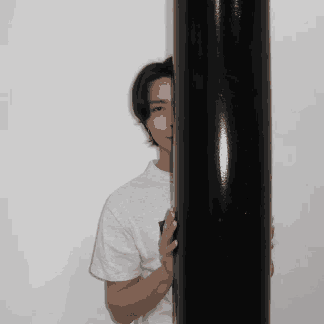 a man standing behind a black pole with his face visible
