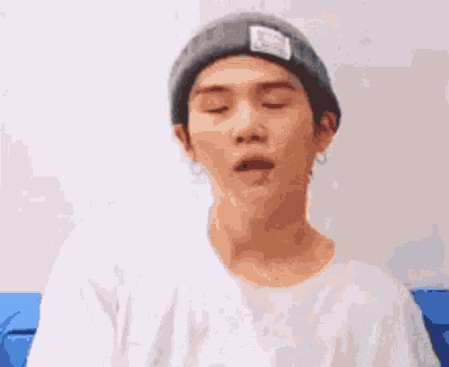 a man wearing a gray beanie and a white shirt is making a funny face .