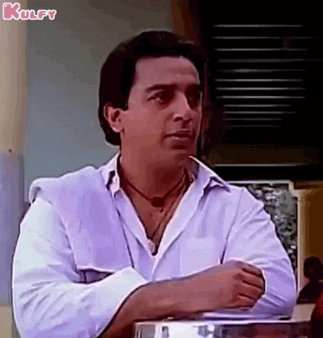 a man in a white shirt is sitting at a table with his hands folded .