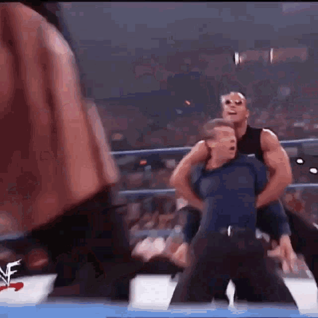 a referee is holding a man in a wrestling ring .