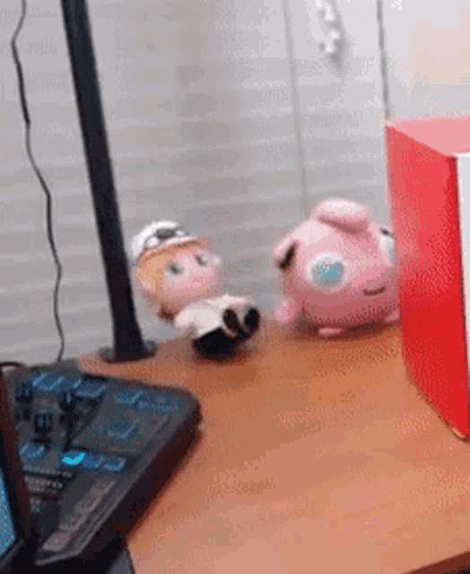 a doll and a stuffed animal are sitting on a desk next to a keyboard