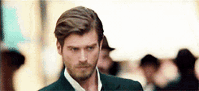 a man with a beard and a suit is walking down a street .