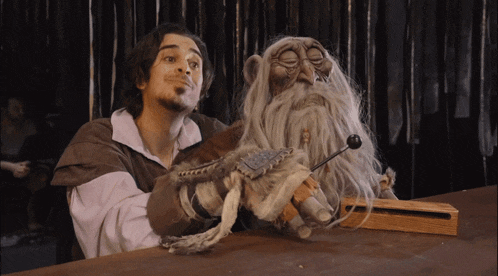 a man with a beard is holding a puppet of an old man with a beard