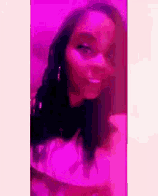 a woman is taking a selfie in front of a pink wall .