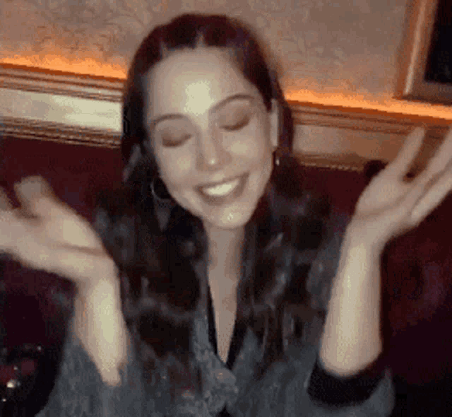 a woman sitting on a couch with her hands in the air
