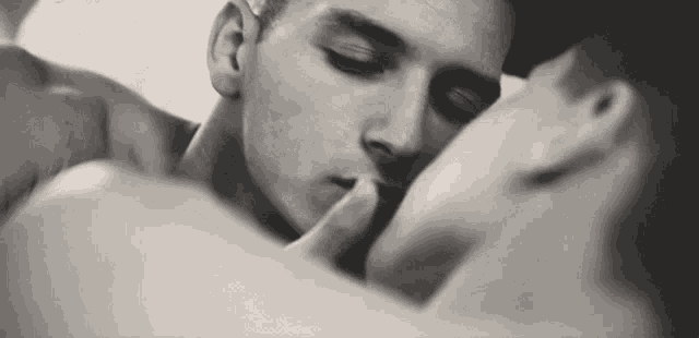 a couple of men are kissing in a black and white photo .