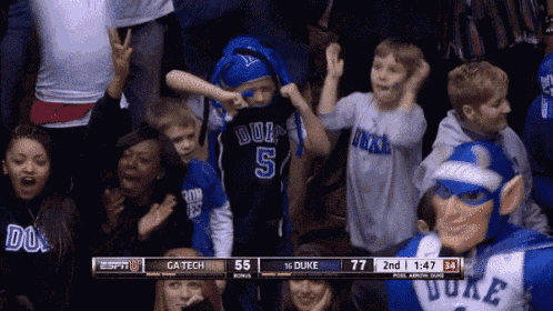 a boy wearing a duke jersey is dancing in the stands