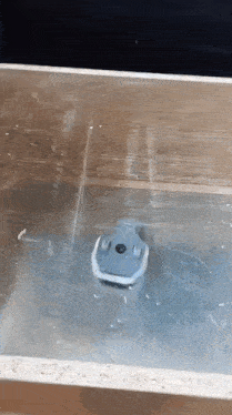 a small toy boat is floating on top of a wooden surface .