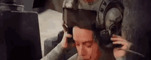 a man wearing headphones and a gas mask is sitting in front of a computer .