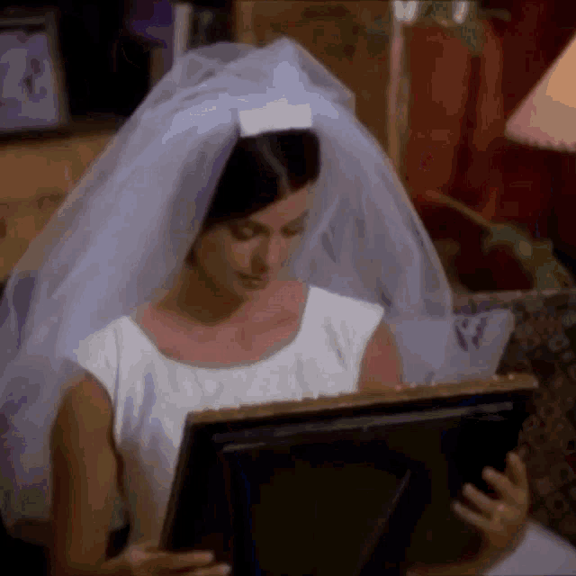 a woman in a wedding dress is looking at a picture frame