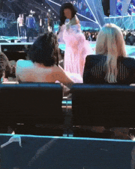 a woman in a white dress is standing in front of a crowd at a concert .