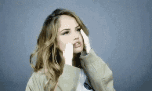 a woman is covering her face with her hands and making a face .