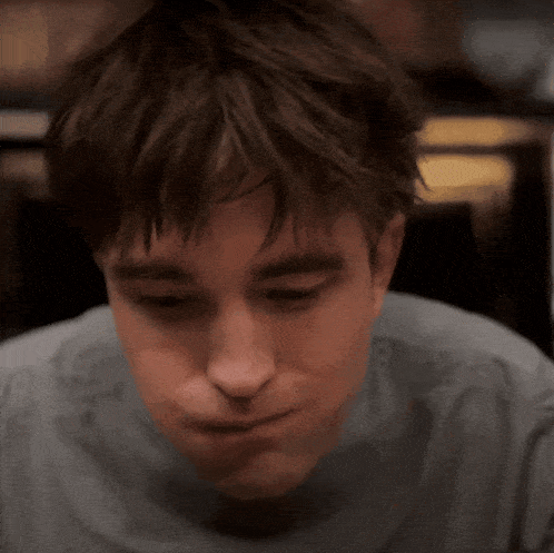 a close up of a person 's face with a gray shirt on