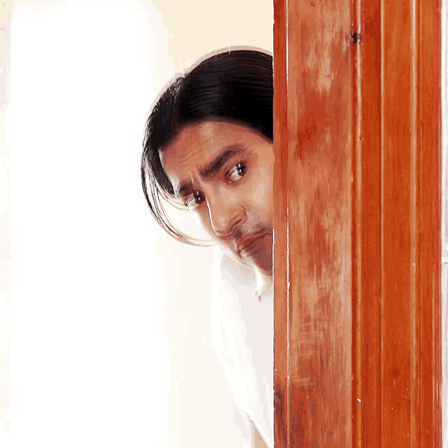 a man is peeking out from behind a door