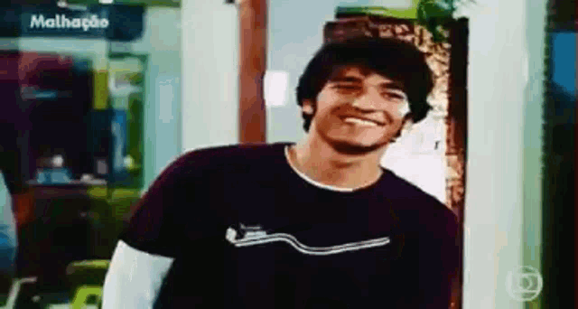 a man wearing a black shirt is smiling in front of a sign that says malhacio