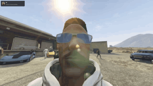 a man wearing sunglasses and a white hoodie is standing in front of a warehouse