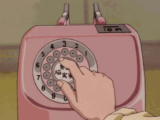 a person is pressing a button on a pink telephone with chinese writing on it