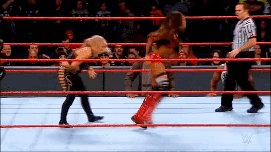 two women are wrestling in a wrestling ring with a referee watching .