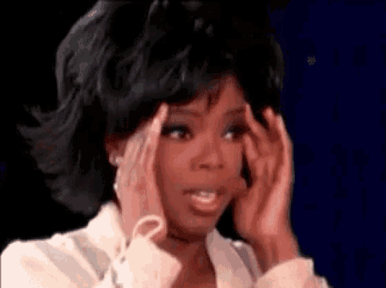 oprah winfrey is holding her head in her hands while talking on a television show .