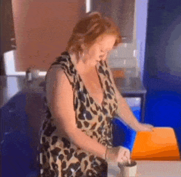 a woman in a leopard print dress is standing in a kitchen stirring a cup of coffee .