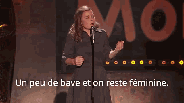 a woman stands in front of a microphone with the words " un peu de bave et on reste feminine " below her