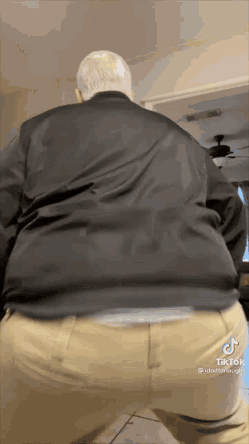 a man in a black jacket and khaki pants is dancing in a room ..