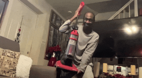 a man is holding a red vacuum cleaner in his hands
