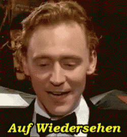 a man wearing a tuxedo and bow tie is smiling with the words auf wiedersehen behind him .
