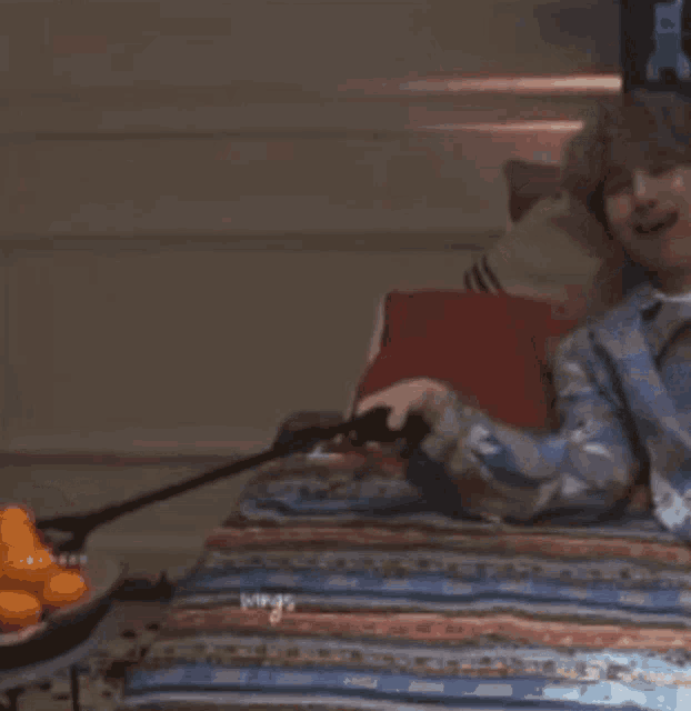a man is laying on a bed with a remote control in his hand and laughing .