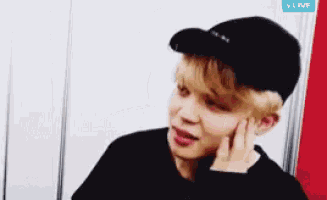 a young man wearing a black hat and a black shirt is talking on a phone .