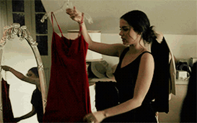 a woman in a black dress is holding up a red dress
