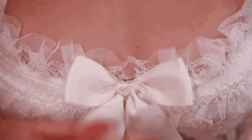 a woman with red nails is wearing a white lace bra and a white bow .