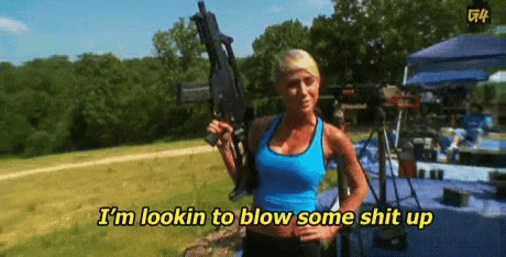 a woman in a blue tank top is holding a gun and says i 'm lookin to blow some shit up ..