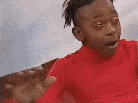 a young boy in a red shirt is making a funny face with his eyes closed and his mouth open .