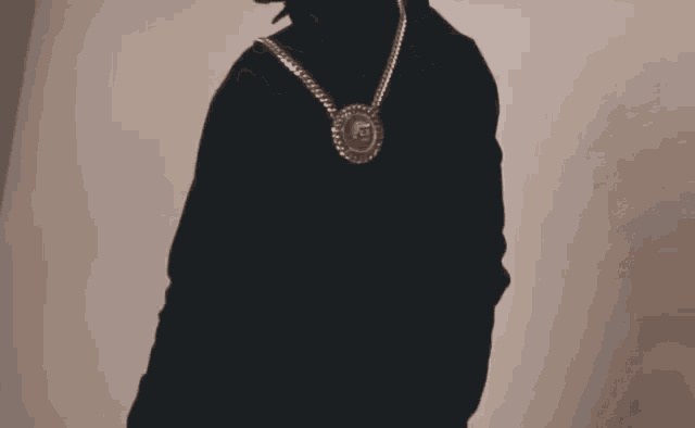 a man wearing sunglasses and a necklace with a pendant that has the letter g on it