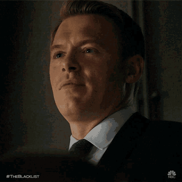 a man in a suit is smiling with his eyes closed