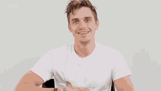 a man in a white t-shirt is smiling and saying yeah !