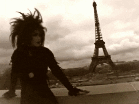 a woman stands in front of the eiffel tower in a black and white photo