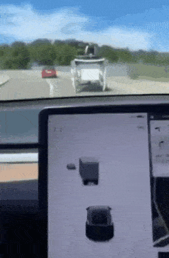 a tesla model s is driving down a highway with a truck behind it .