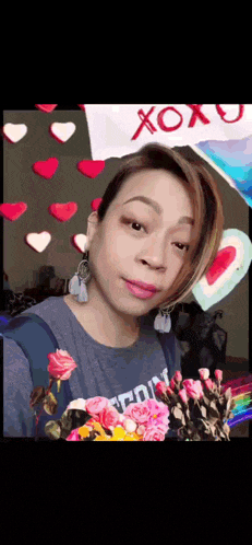 a woman is holding a bouquet of flowers in front of hearts and a sign that says xoxo