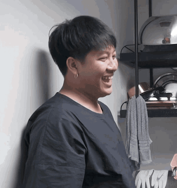 a man in a black shirt is smiling in front of a shelf
