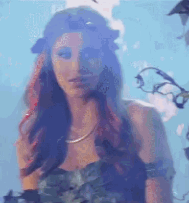 a woman with red and blue hair is wearing a leafy dress
