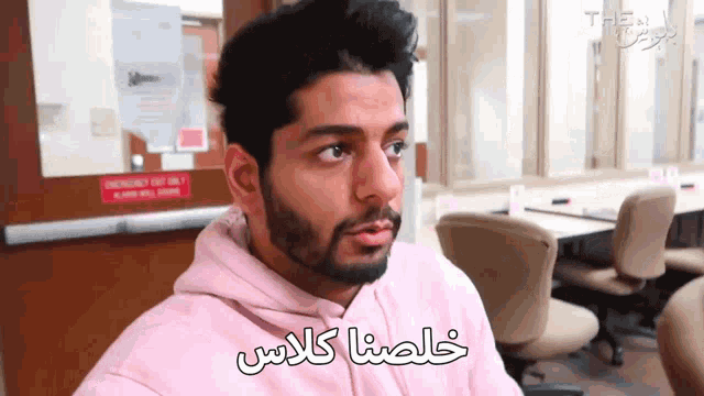 a man wearing a pink hoodie with arabic writing on the front