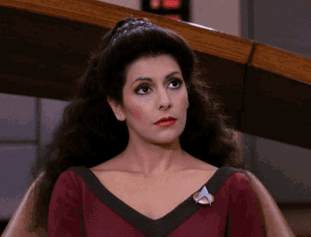 a woman in a red dress has a star trek pin on her shoulder