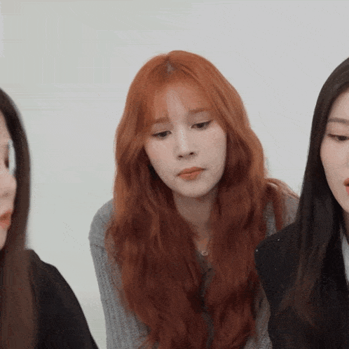 a woman with red hair looks at the camera with two other women