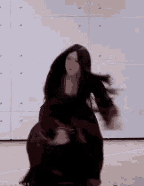 a woman in a long black dress is dancing with her arms outstretched .